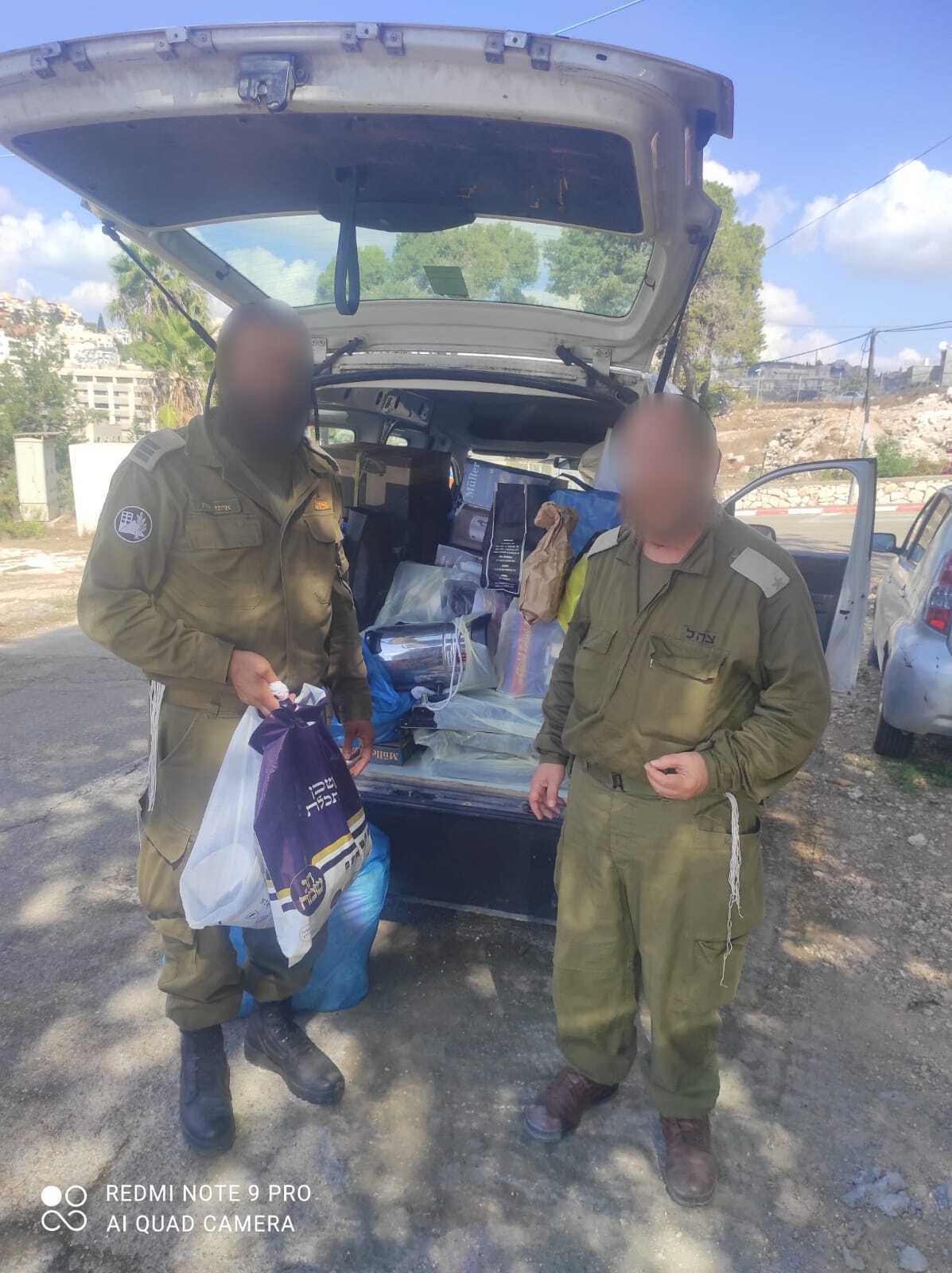 Soldiers beside a vehicle filled with delivered supplies, with faces obscured for privacy