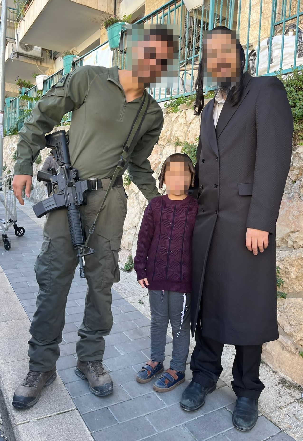 A soldier standing with members of a family, with faces obscured for privacy